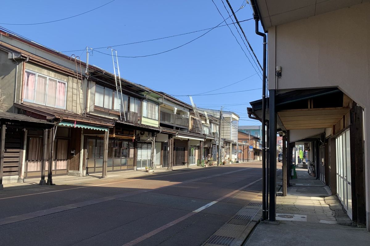 青空の下に雁木のある家並みが続く、新潟県上越市高田・大町の風景